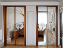 Спальня «Гарда» изготовлена из массива вишни. Встроенные шкафы купе в раздвижной системе Kapo de Monte «Багетное золото» с зеркалами с пескоструйным рисунком.
