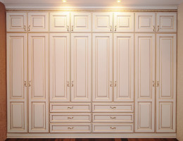 Платяной встроенный распашной шкаф «Валенсия» изготовлен из массива ясеня под ванильной эмалью с золотой патиной.